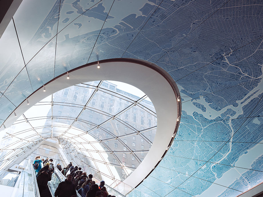 People use an escalator with glass ceiling overhead at Moynihan Train Hall